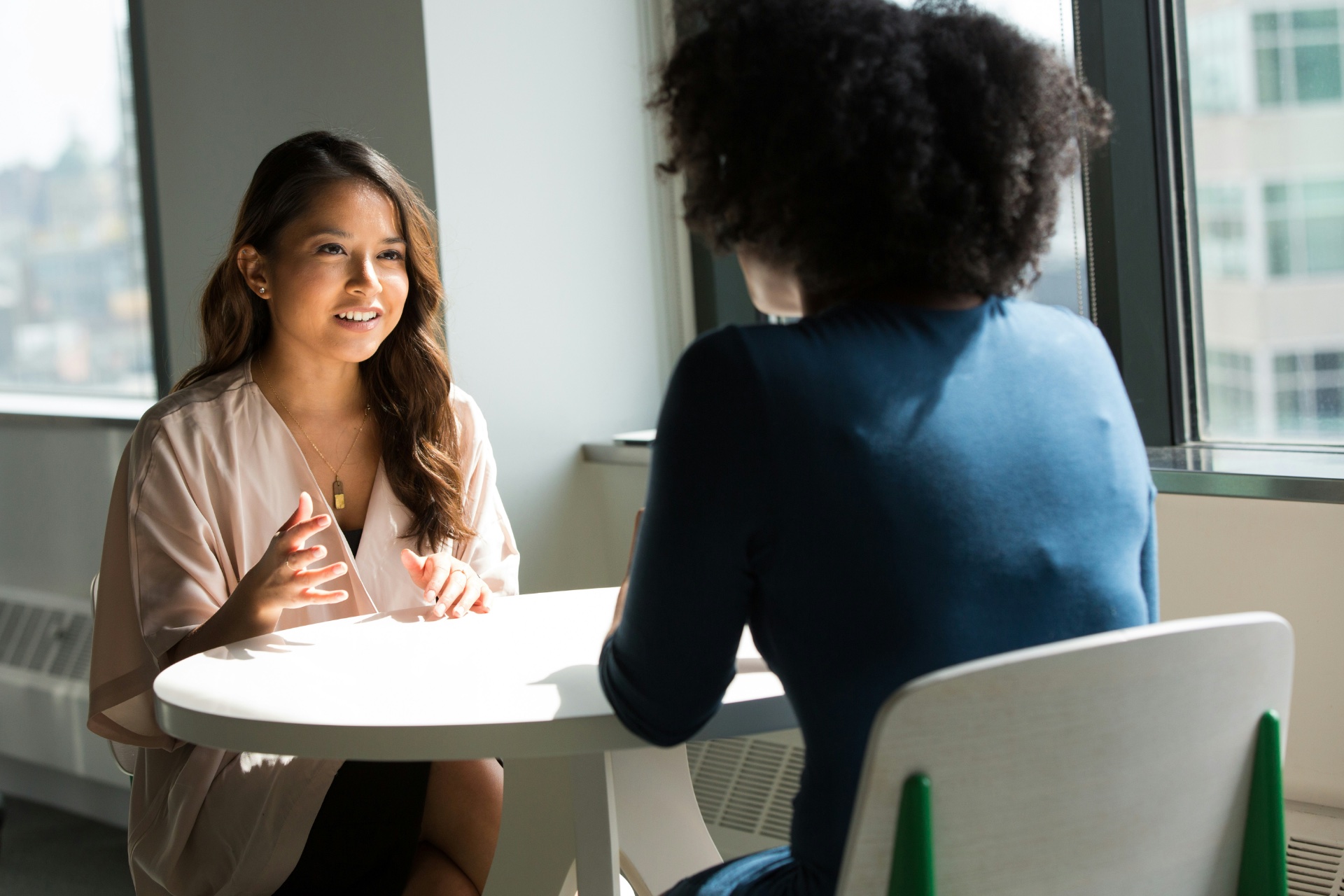 A circle of diverse technology executives participating in a facilitated peer group session. They are seated around a contemporary table, actively listening and engaging with each other. One person is speaking with conviction, while others nod or take notes. The setting is a comfortable, private meeting room with soft, encouraging light, emphasizing collaboration and trust.